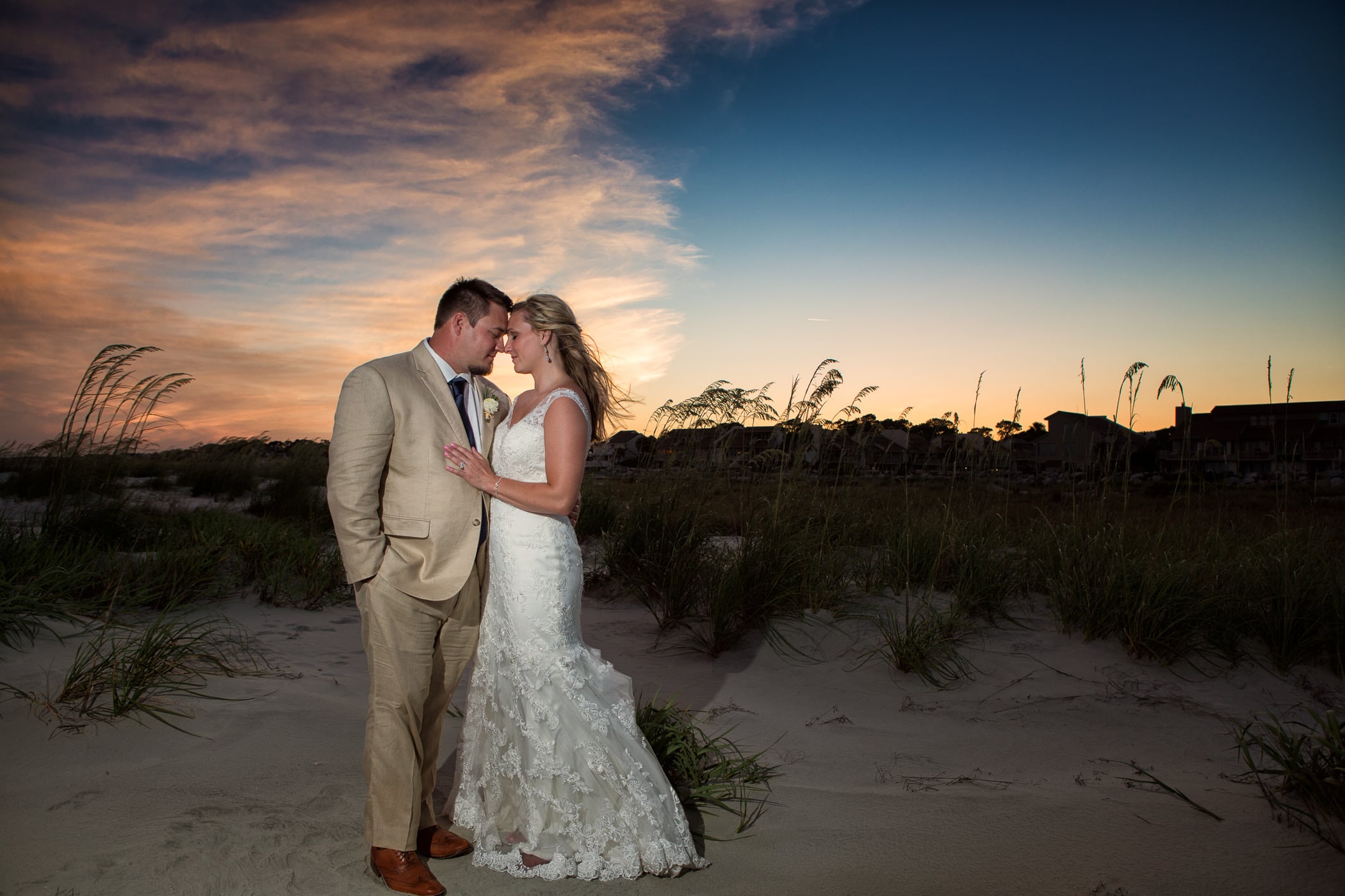 bride and groom kissing on beach at sunset