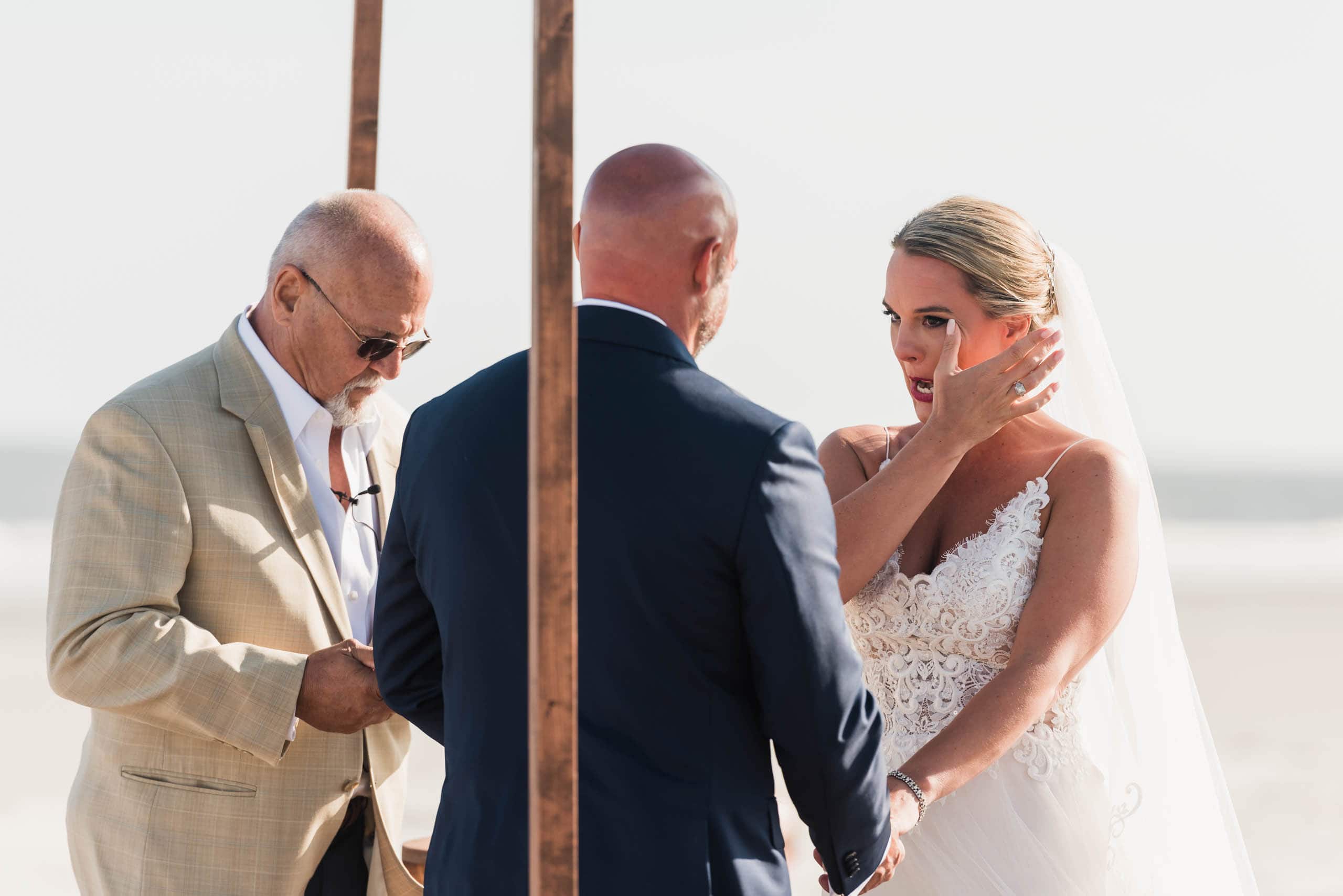 Bride wiping tear from her cheek during beach wedding ceremony on Fripp Island by Susan DeLoach Photography SC Wedding Photographer 