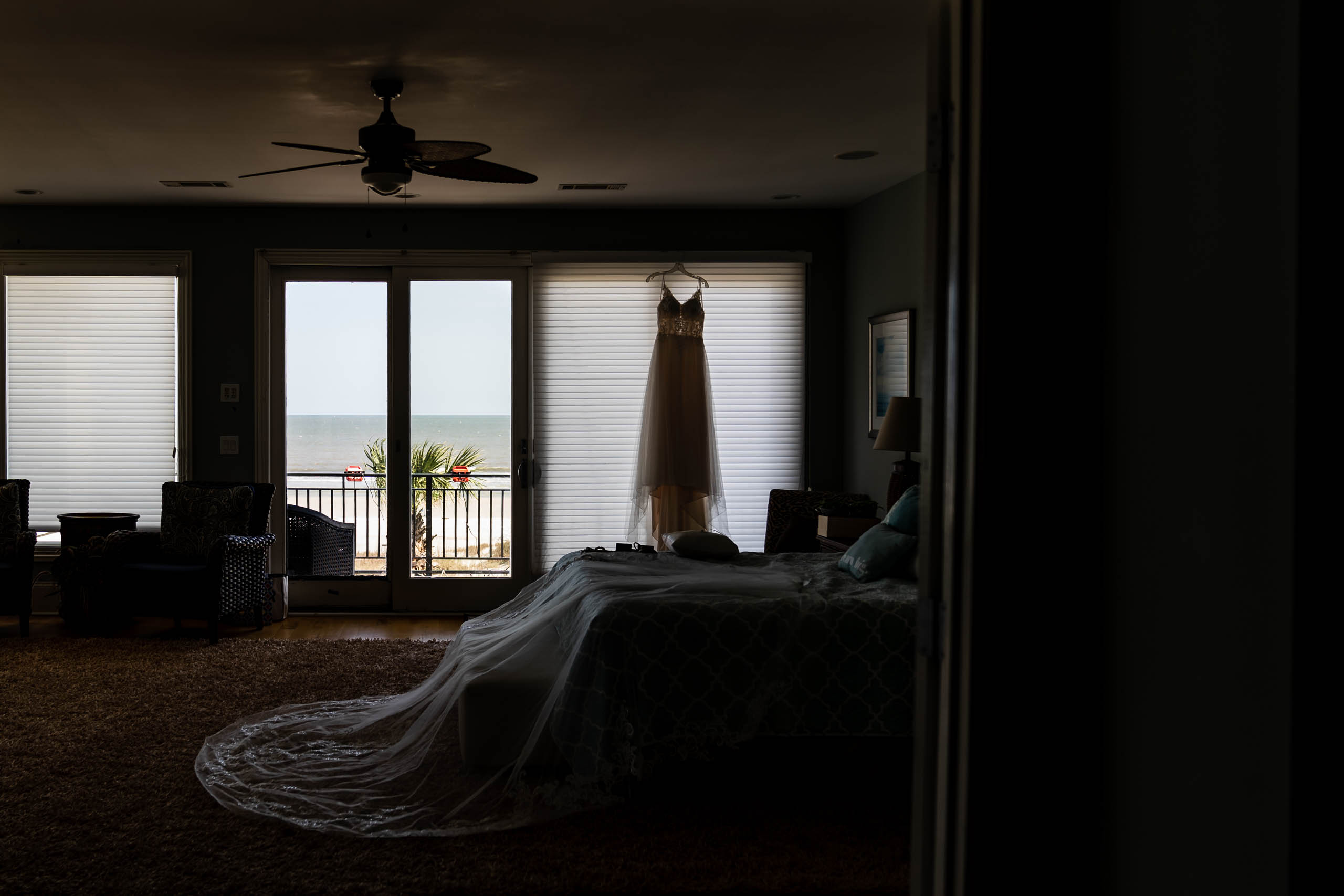 Wedding dress hanging in window of beach house on Fripp Island by susan deloach photography sc wedding photographer 