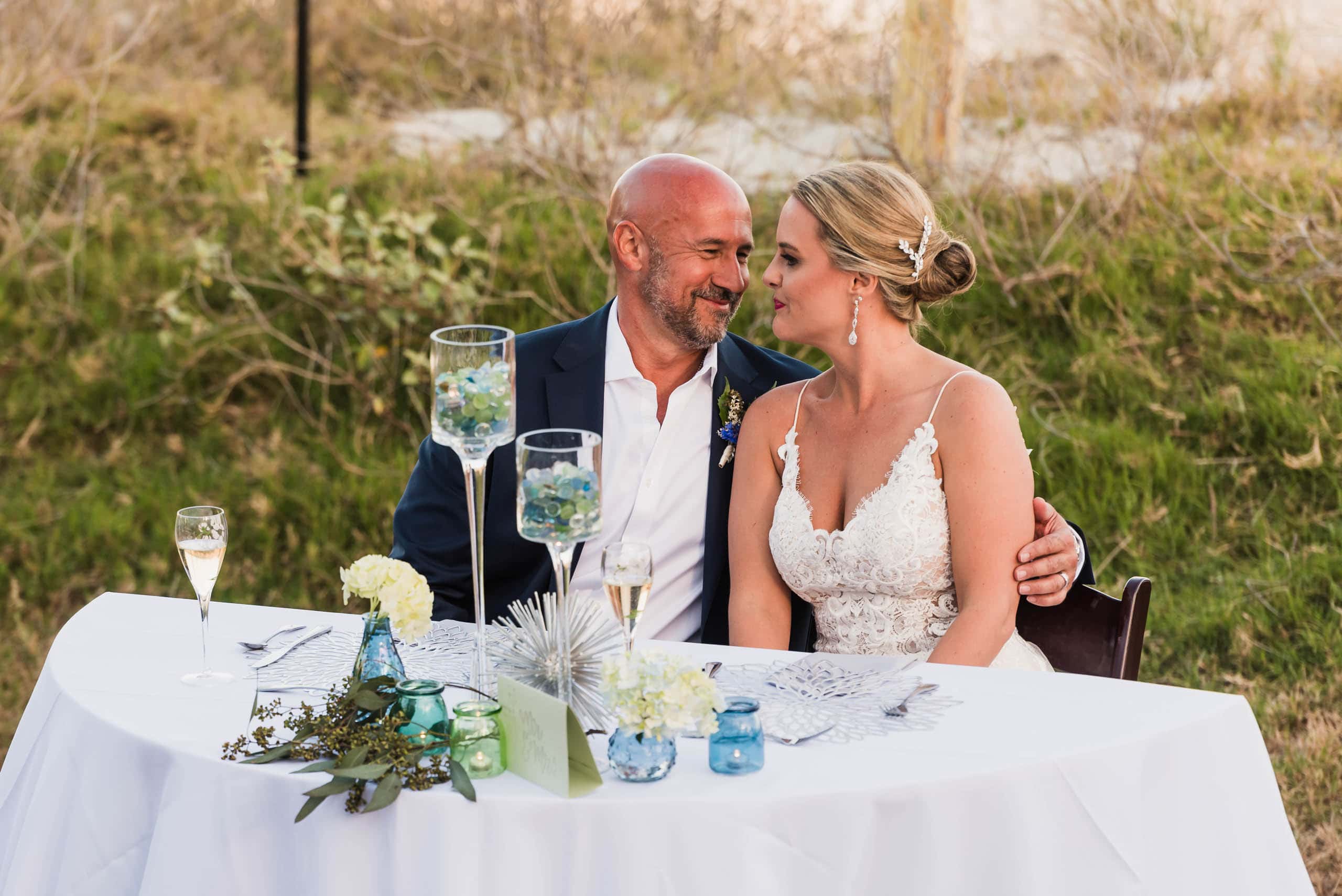 Bride and Groom sitting at the sweetheart table during wedding reception on the beach at Fripp Island by Susan DeLoach Photography SC Wedding photographer