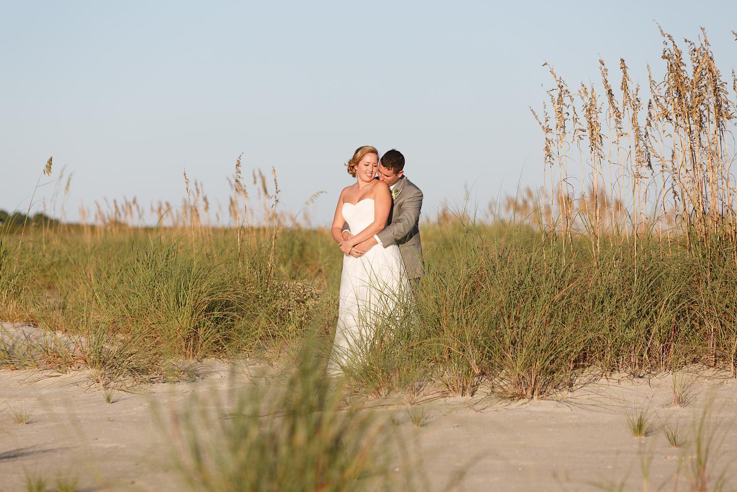 bride and groom embracing on sand dunes